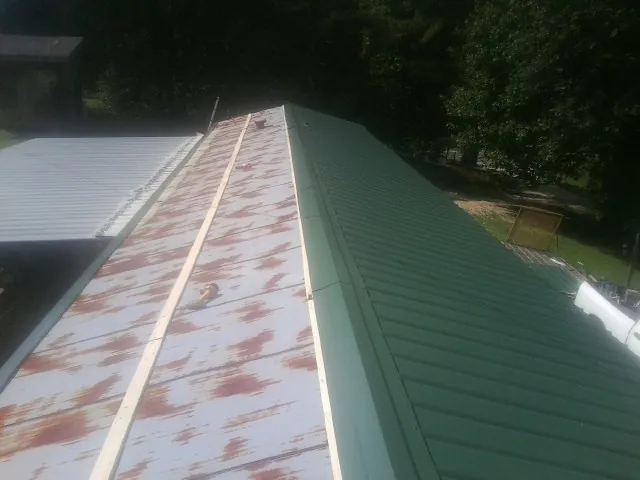 Old rusted panels beside newly installed green metal roofing — Wind Damage Roof Repair by Roofing Brothers in Marydel