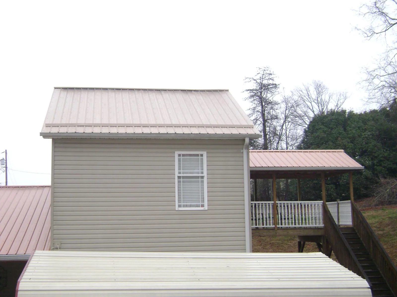 Tan metal roofs on a two story addition and attached porch, from a Roof Replacement job in Marydel